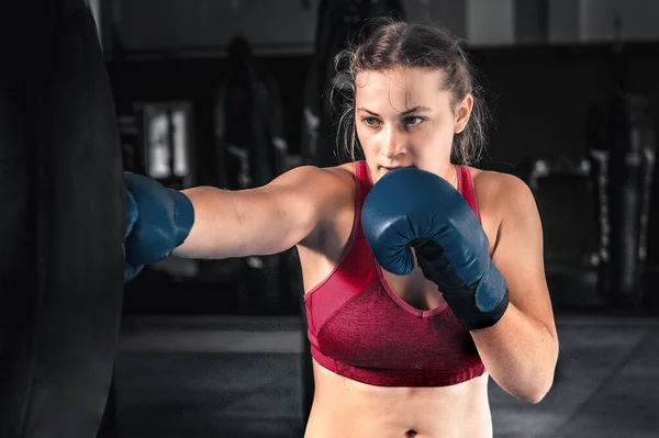 Attractive young woman boxing at the gym. Female boxer preparing for training in boxing club