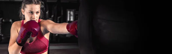 Attractive young woman boxing at the gym. Female boxer preparing for training in boxing club. Banner design