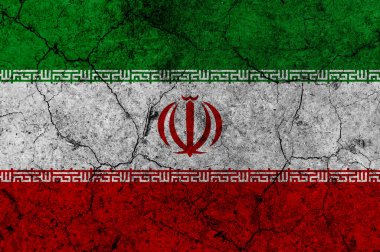 Eski bir duvar yüzeyine İran bayrağı çizilmiş. Görünür çatlaklar ve grunge dokusuyla İran ulusal bayrağına hasar vermiş. Siyasi kriz, çatışma, jeopolitik gerilim veya ulusal sembol geçmişi kavramı.