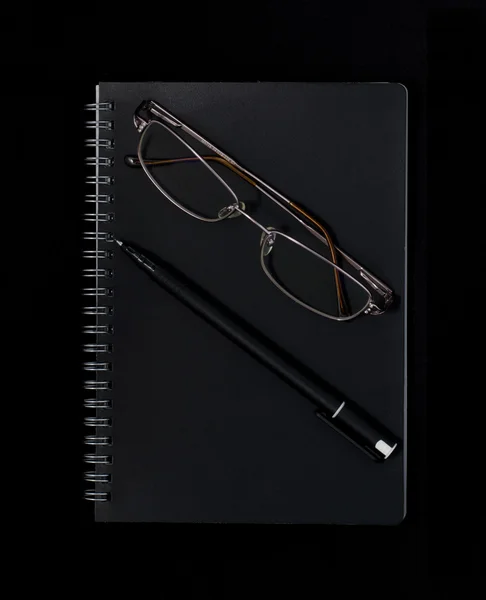 Carnet, stylo et lunettes sur fond sombre — Photo