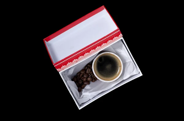 Una taza de café en una caja de regalo sobre un fondo negro — Foto de Stock