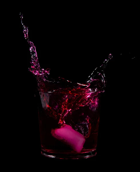 Éclaboussure de glaçon dans un verre d'eau rouge ou de boisson — Photo