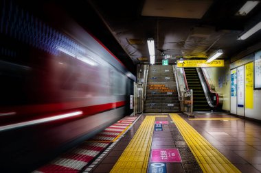 Boş merdivenlere ve Tokyo, Japonya 'daki bir istasyonun yürüyen merdivenine bir metro treni varır..