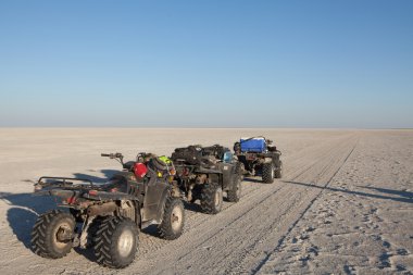 Quad bikes line up on a salt pan clipart