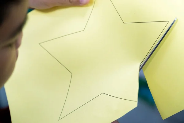 The boys are cutting the paper in a star pattern