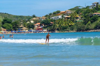 Geriba plajı, Buzios, Rio de Janeiro, Brezilya - 22 Aralık 2019: Güney Atlantik kıyısında sörf. Güneşli bir yaz gününde su sporları yapan güzel bir genç kadın. Tropik plaj, Praia da Geriba.