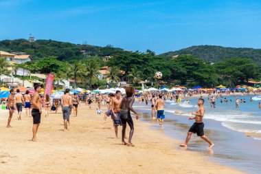 Geriba plajı, Buzios, Rio de Janeiro, Brezilya 22 Aralık 2019. Bir grup erkek sahilde futbol oynarken eğleniyor. Etraflarında bir sürü insan var. Praia da Geriba.