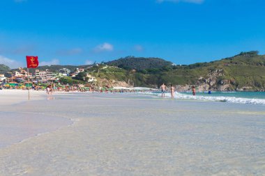 ARRAIAL DO CABO, RIO DE JANEIRO, BRAZİL - 26 Aralık 2019 Praia Grande plajının panoramik manzarası. Beyaz kum, berrak ve şeffaf deniz suyu. Bazı insanlar güneşli günün tadını çıkarıyorlar. Arkaplanda tepeler.