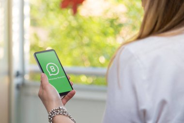 ROSARIO, ARGENTINA - 29 Aralık 2020: Whatsapp Business uygulama logosu cep telefonu ekranında genç iş kadınının elinde. Elinde akıllı telefon tutan bir kadın. İnternet iletişimi.