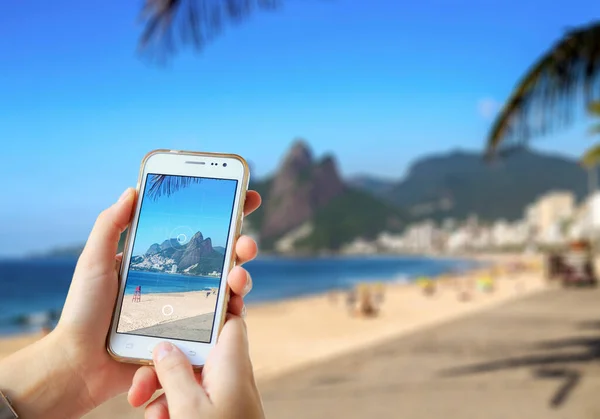 Ipanema Plajı 'nda cep telefonuyla fotoğraf çeken bir kız. Brezilya, Rio de Janeiro 'da bir akıllı telefon kamerasıyla fotoğraf çekmek..