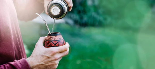 Sıcak suyla eş hazırlayan bir adam. Kabak çiftinin içinde yerba var. Orta yaşlı Latin Amerikalı adam gün batımının tadını çıkarıyor. Kopyalama alanı olan sancak biçimi.