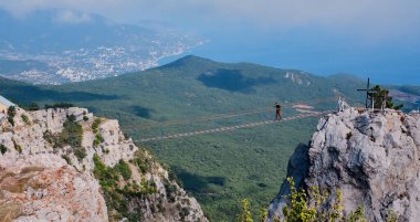Yalta, Ukrayna - 20 Eylül 2020: Güzel dağ manzarası Ai Petri yaylası Bir erkek aşırı eğlence için dağ siperleri arasında asma köprü boyunca yürüyor