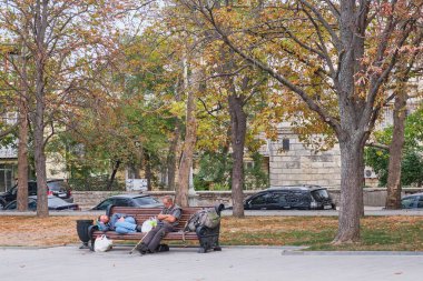 Sivastopol, Ukrayna - 25 Eylül 2020: İki evsiz orta yaşlı adam sonbahar parkında bir bankta dinleniyor..