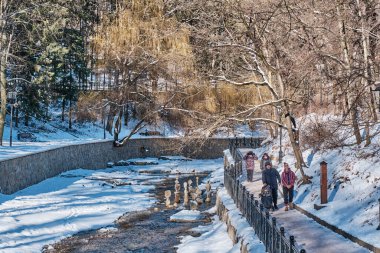 Kislovodsk, Russia - January 23, 2021: Winter or spring landscape. Olkhovka River. People walk along the embankment in the beautiful national resort park