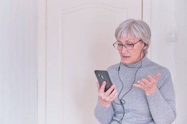 Gri saçlı, gözlüklü, boğazlı ve cep telefonuyla konuşan son sınıf öğrencisi bir kadın. İnsanlar iletişim kurar. Yaşam tarzı anı.