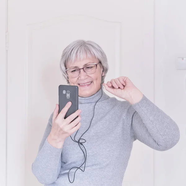 Starší žena mluví doma na mobilním telefonu. — Stock fotografie