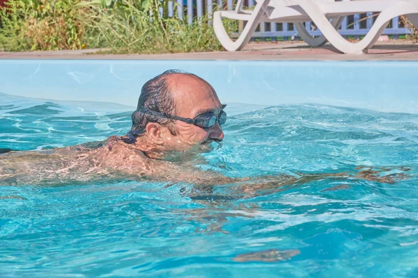 Un hombre nada en una piscina en el patio — Foto de Stock