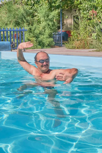 Un hombre nada en una piscina en el patio — Foto de Stock