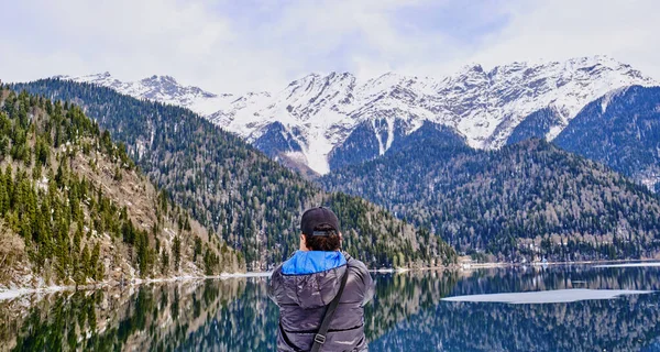 Un hombre en toma una foto de un hermoso paisaje de invierno de las montañas del Cáucaso y el lago Ritsa —  Fotos de Stock