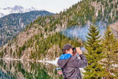 Bir adam, Kafkasya dağları ve Ritsa Gölü 'nün güzel bir kış manzarasının fotoğrafını çeker.