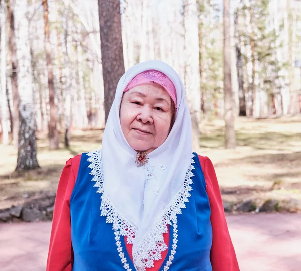 Half-length portrait of an elderly Muslim woman in traditional festive dress , Russia