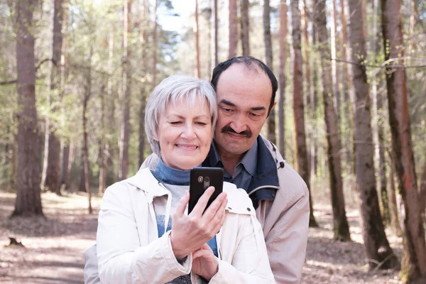 Elderly interracial couple park looking together at a mobile phone screen