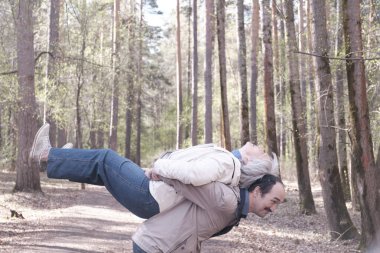 Elderly interracial couple fooling around in a spring forest park.