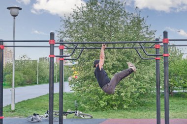 Kıdemli Asyalı adam parktaki spor sahasında şehrin arka planına karşı antrenman yapıyor..