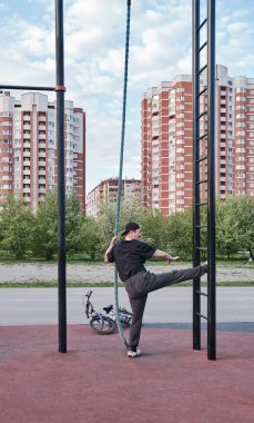 Şehir parkındaki spor sahasında yaşlı Asyalı adam eğitimine karşı şehir manzarası.