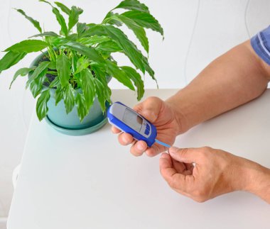 Yaşlı adamın elleri kan şekeri seviyesini ölçüyor.