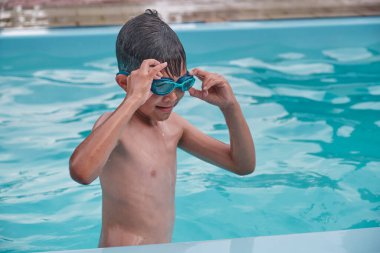 Asyalı çocuk havuza yüzme gözlüğü takıyor..
