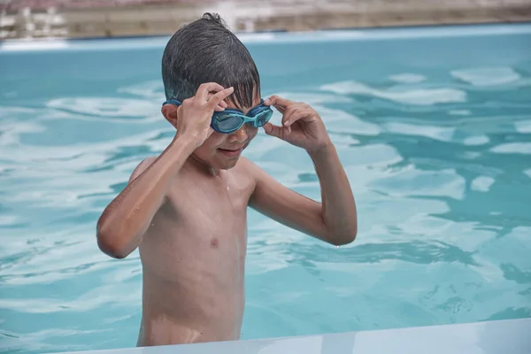 Ásia menino colocando no natação óculos no piscina. — Fotografia de Stock