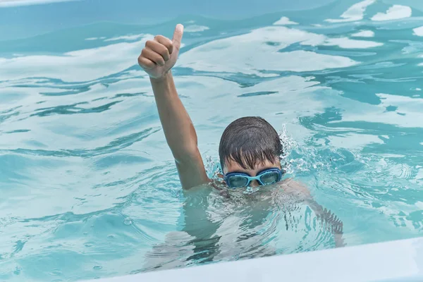 Asiático menino em óculos de natação azul mergulha na água na piscina — Fotografia de Stock