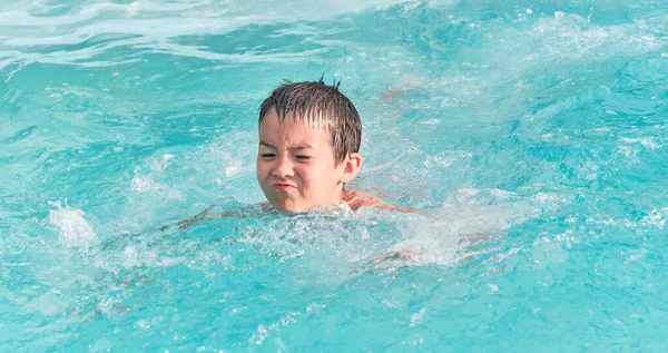 Ázsiai fiú úszik medencében a nyári napon. — Stock Fotó
