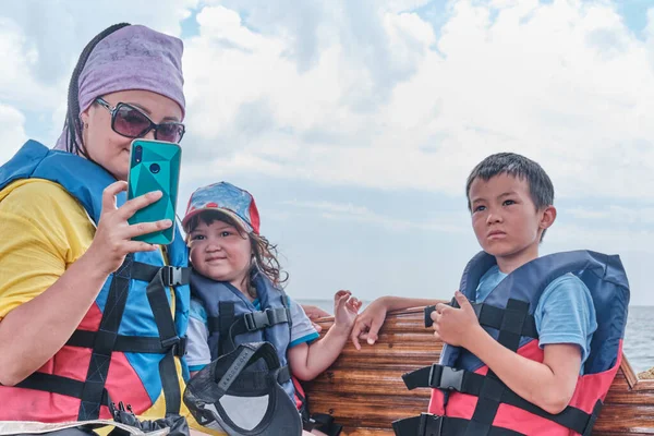 Молодая красивая азиатка и ее дети делают селфи во время прогулки на лодке по морю — стоковое фото
