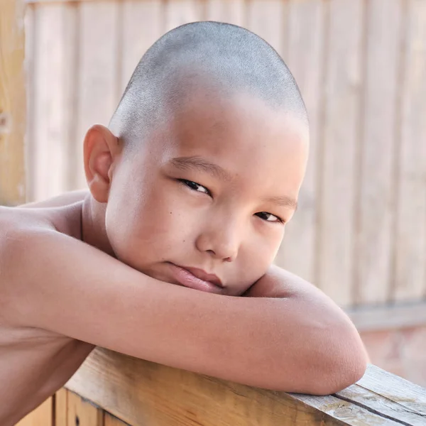 Portrait of tanned asian boy, hair cut bald, looking at camera — Zdjęcie stockowe