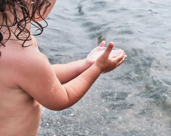 Niña pequeña está sosteniendo cuidadosamente una pequeña medusa transparente — Foto de Stock