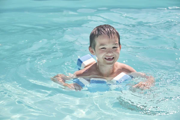 Pequeno menino asiático está aprendendo a nadar na piscina exterior — Fotografia de Stock