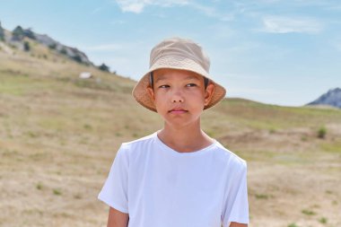 Beyaz tişörtlü ve şapkalı Asyalı bir çocuğun portresi.