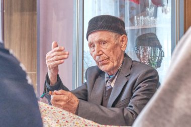 Molla kırsal evde elleriyle el kol hareketi yapıyor.