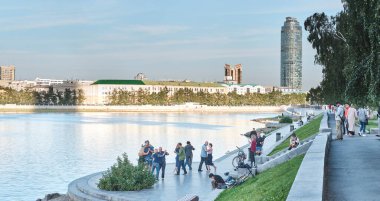 Dans eden çiftler, Iset nehrinin kenarında yürüyen insanlar. Yaz şehri manzarası.