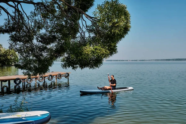 Asiatico più vecchio uomo su sup pensione su calmo lago. — Foto Stock