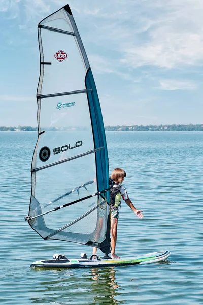 Vindsurfingträning. Pojke flyter ombord med segel på sjön — Stockfoto