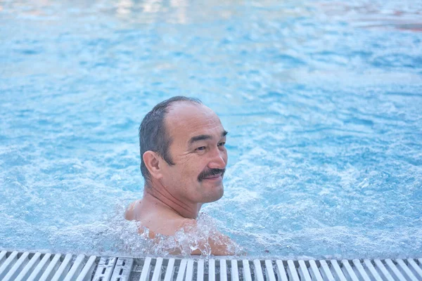 Sonriendo hombre asiático maduro en piscina termal al aire libre con hidromasaje. — Foto de Stock