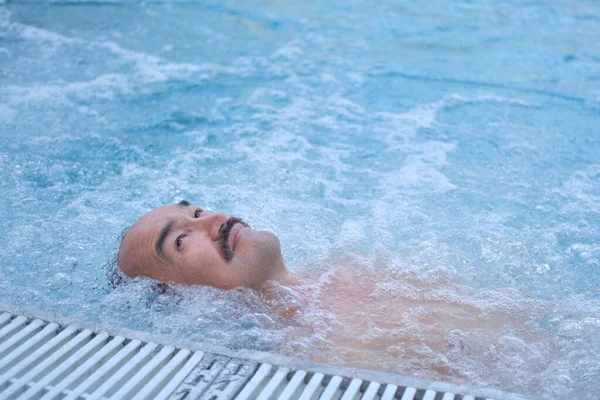 Feliz hombre asiático maduro acostado en el agua relajarse en la piscina termal al aire libre con hidromasaje. — Foto de Stock