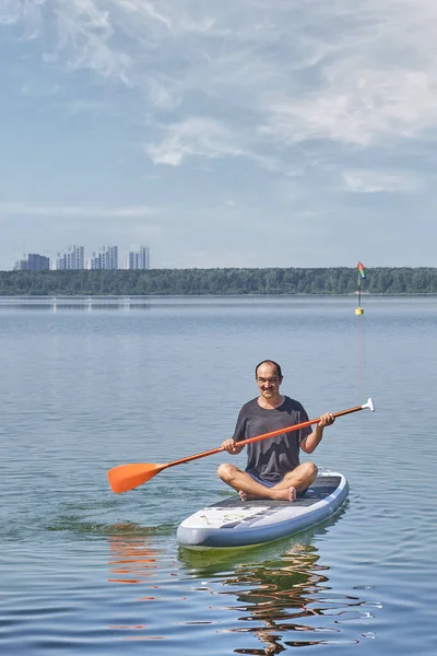 Asiatico più vecchio uomo su sup pensione su calmo lago. — Foto Stock