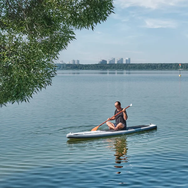 Літній азіатський чоловік на дошці спокійного озера.. — стокове фото