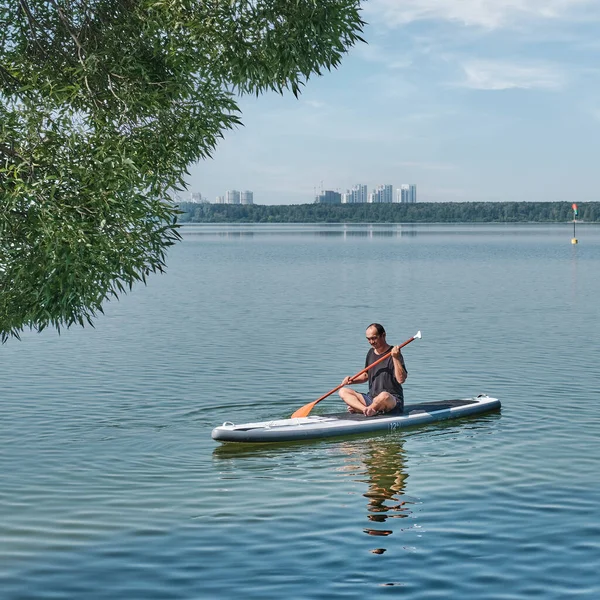 Asiatico più vecchio uomo su sup pensione su calmo lago. — Foto Stock