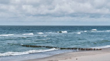 Güzel deniz manzarası, eski ahşap dalgalar, kumlu sahil ve bulutlu gökyüzü..