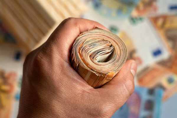 Man hand holding roll of euro money bill on a money background, Euro money of European Union